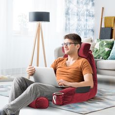 a man sitting on a bean bag chair using a laptop computer while holding a cup