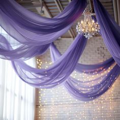 a room with purple drapes and a chandelier hanging from the ceiling