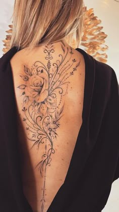 the back of a woman's neck with flowers and vines tattooed on her lower back