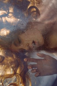 a close up of a person's face through a window with water on it