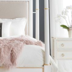 a white bed with pink fur on it and two nightstands in front of the bed