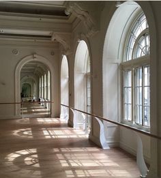 an empty hallway with arched windows and wooden floors