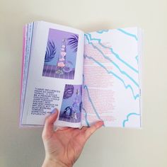 a person is holding an open book with pictures on it and the pages are purple