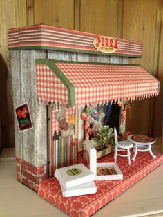 a doll house made to look like a small store with red and white checkered awning