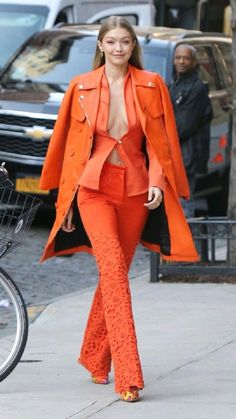 a woman in an orange outfit is walking down the street