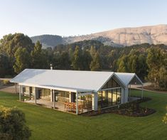 an aerial view of a house in the middle of a field with mountains in the background