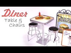 there are two stools and a table that is next to a sign with a burger on it