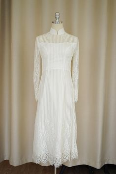 a white dress on a mannequin stand in front of a curtain