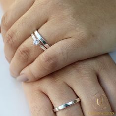 two hands holding each other with wedding rings on their fingers and one has a diamond in the middle