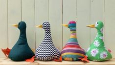 three stuffed ducks sitting next to each other on a wooden shelf with white boards behind them