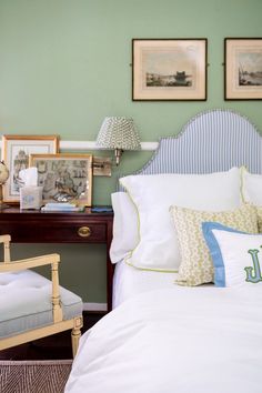 a bedroom with green walls and white bedding, two pictures on the wall above the bed