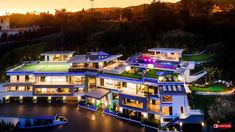 an aerial view of a mansion at night with the lights on and water in front