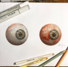 pencils are laying next to two drawings of eyeballs