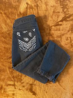 a pair of jeans with an embroidered face on them