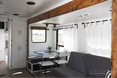 the interior of a mobile home with a couch, table and kitchenette in it