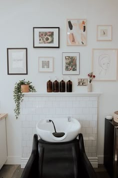 a white sink sitting in the middle of a bathroom next to a wall with pictures on it