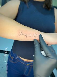 a woman is getting her arm tattooed with the word jogagumi on it