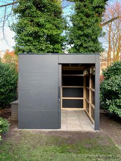 an outdoor storage shed in the middle of a garden with trees and bushes around it