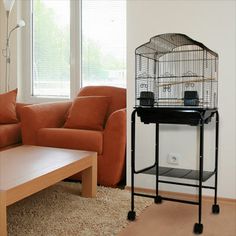 a living room with a bird cage on top of a table next to a couch