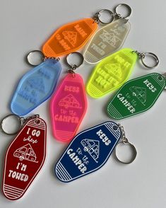 six keychains with different designs and words on them, all in various colors