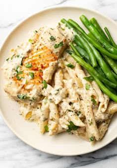 a white plate topped with pasta and green beans