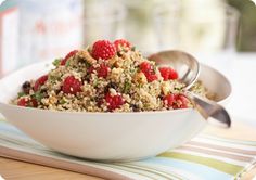 a white bowl filled with raspberries and granola on top of a table