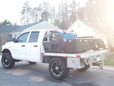 a white truck parked in front of a house with luggage on the back of it's flatbed