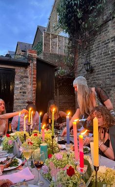 a group of people sitting around a dinner table with lit candles in front of them