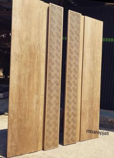 two large wooden doors sitting next to each other in front of a metal structure with an intricate design on it