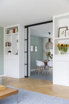 a living room filled with furniture and bookshelves next to a dining room table