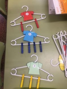 some clothes hangers made out of paper and plastic pegs on a green table