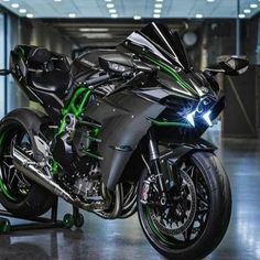 a black and green motorcycle is parked in a parking garage with its lights turned on