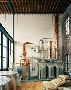 a room filled with lots of metal tanks next to wooden flooring and large windows