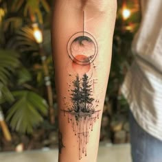 a person with a tattoo on their leg that has an image of trees in the background