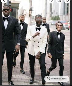 three men in tuxedos are walking down the street with one man wearing sunglasses