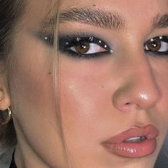 a close up of a woman with makeup on her face and wearing gold hoop earrings