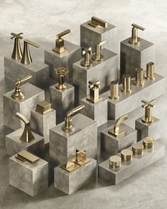 an assortment of gold faucets and soap dispensers on concrete blocks