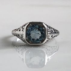 Details: Beautiful Edwardian Aquamarine 18K white gold filigree ring. This ring is very sweet, with delicately detailed filigree with tiny French fleur-de-lis . The aquamarine measures 7.3mm round. The ring is stamped 18K on the inside of the band. Measurements: Ring measures a size 6 1/2 US. It can be re-sized for a fee. Condition: The overall all condition of this ring is very good. Please ask all questions prior to placing an order. Fine Jewelry Sapphire Ring With Filigree, Luxury Silver Engraved Filigree Ring, Luxury Engraved Silver Filigree Ring, Anniversary Sapphire Ring With Filigree Fine Jewelry Style, Anniversary Fine Jewelry Sapphire Ring With Filigree, Silver Oval Filigree Ring In 14k Gold, Silver 14k Gold Oval Filigree Ring, White Gold Oval Filigree Ring Engraved, 14k White Gold Filigree Ring Jewelry