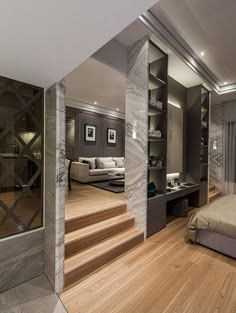 a bedroom with wood flooring and white walls next to a staircase leading up to a bed