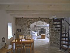 an open living room and dining area with stone walls