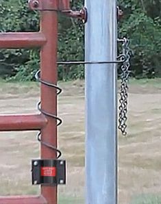 a red fire hydrant sitting next to a metal pole with chains hanging from it