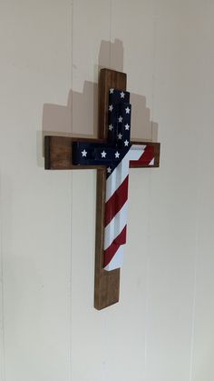 a wooden cross with an american flag tie hanging from it's side on a wall