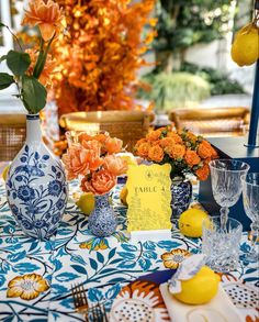 the table is set with blue and white vases, lemons, and orange flowers