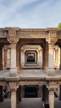 the inside of an old building with pillars and arches on it's sides as well as people walking around