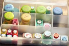 a plastic container filled with lots of different types of buttons and pens on top of a wooden table