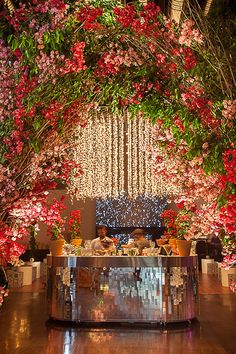 an outdoor event with flowers and lights on the ceiling