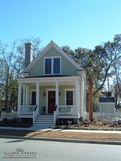 a small house with white picket fence around the front door and porches on both sides