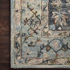 an area rug with blue and white colors on top of a wooden floor next to a wall