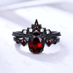 a close up of a ring with a red stone in the center and two white diamonds on each side