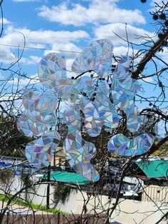 a tree with many circular mirrors hanging from it's branches in front of a blue sky